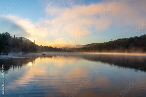 vue large d'un cygne gonflable qui flotte sur un lac super calme lors d'un lever de soleil enflammé