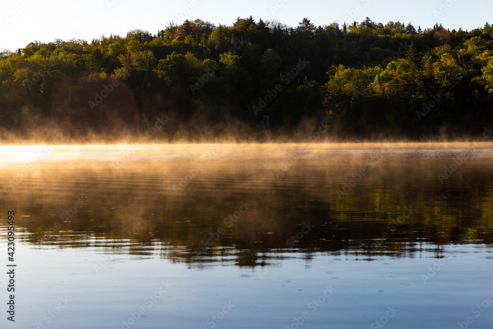 Fototapeta premium brume matinale sur le lac au matin lors d'un lever de soleil enflammé