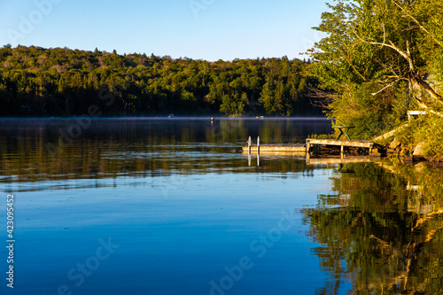 vue d'un quai sur la rive d'un lac lors d'un lever de soleil d'une journée d'été avec ciel bleu 