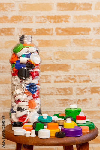 Garrafa pet contendo inúmeras tampas de plástico de diversas cores, formas e tamanho. photo