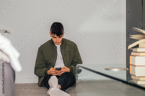 teenage boy at home with mobile phone on the floor