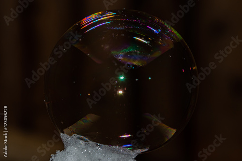 Close up of round fragile soap bubble with rainbow colours.