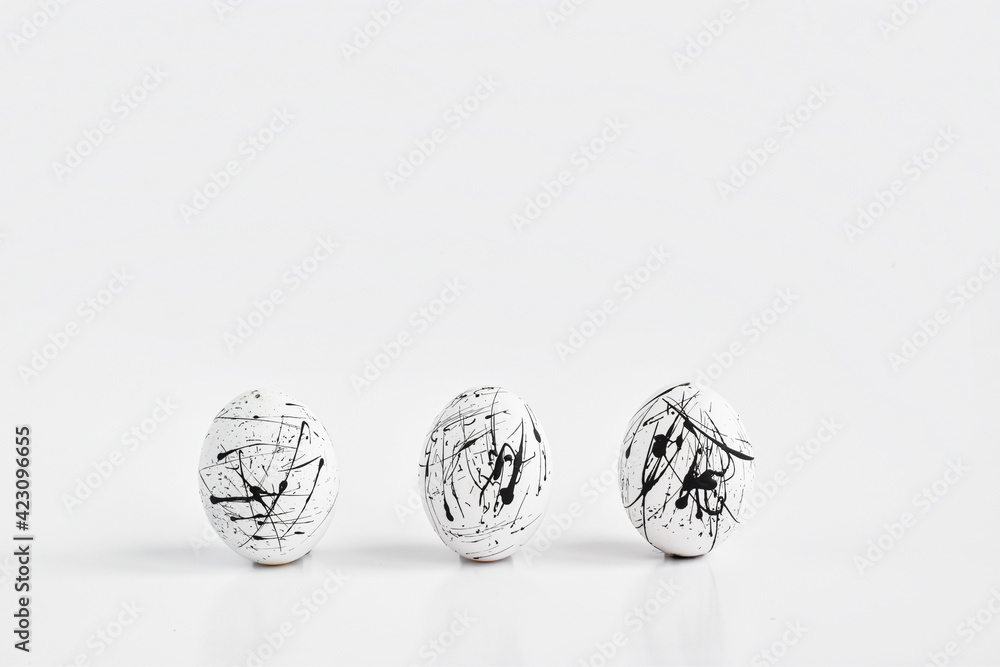 Three white eggs speckled on white.The minimal concept of Easter. Easter greeting card with a space for text. Geometry. copy space Three white eggs speckled on white.The minimal concept of Easter. Easter greeting card with a space for text. Geometry. copy space