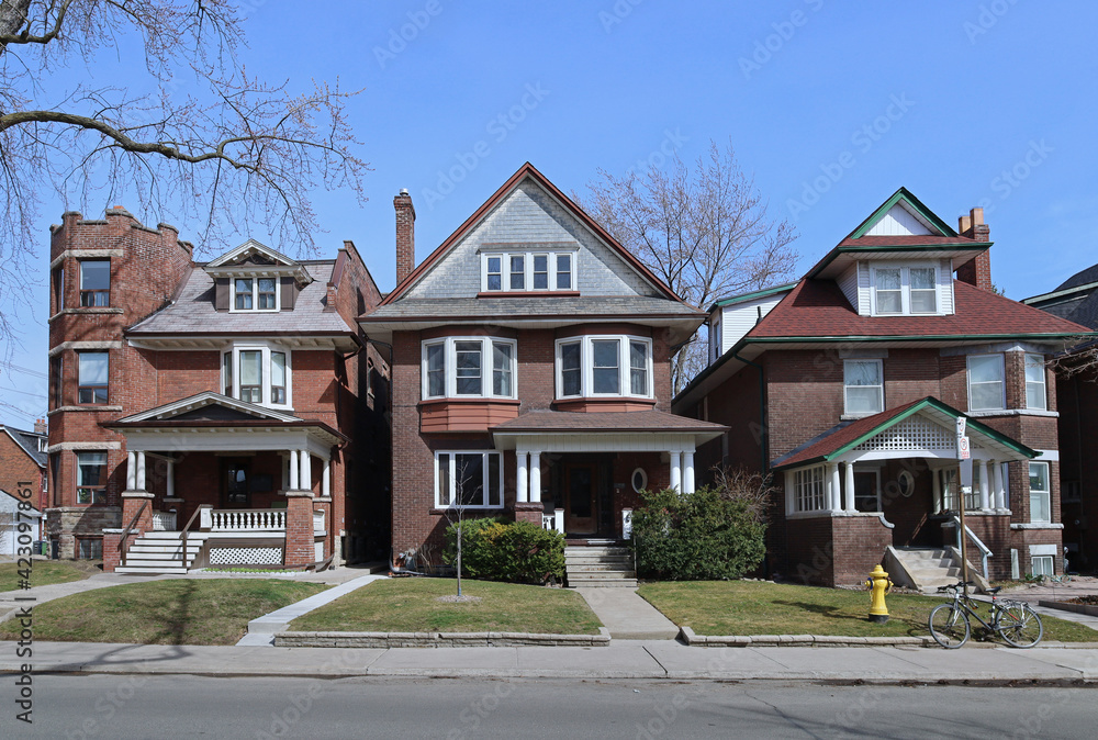 Fototapeta premium Residential street with traditional detached brick houses with front lawns