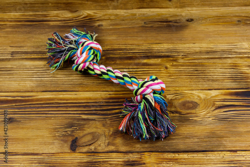 Colorful rope toy for dog on wooden background. Top view