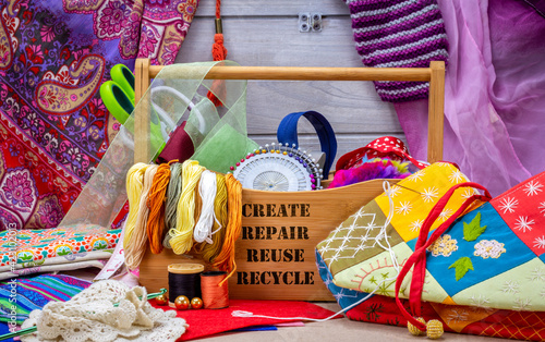 Sewing box with create, repair, reuse and recycle text surrounded by sewing tools, fabric and thread. Craft, repurpose and upcycle textiles and clothing to reduce waste for sustainable living.