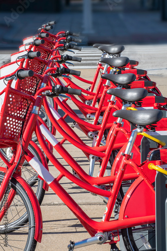 Red rental bikes line a city street © Michael O'Neill