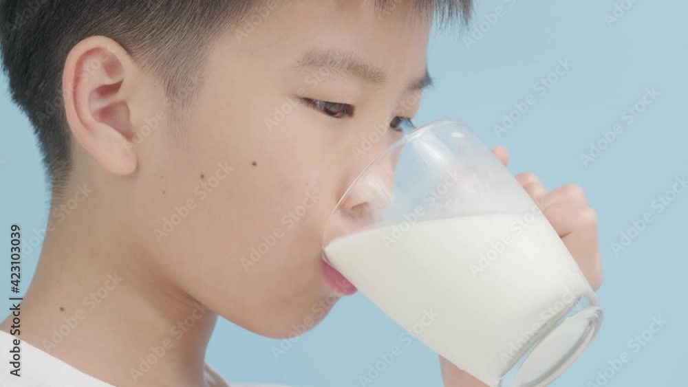 Selective focus young Asian boy milk from glass on blue background Selective focus young Asian boy milk from glass on blue background