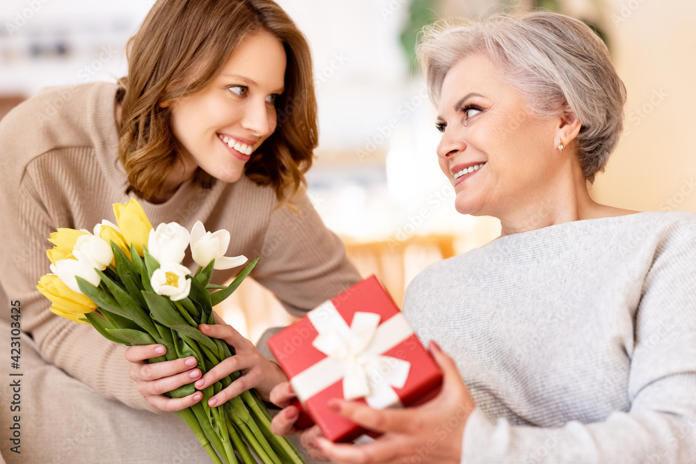 Positive women giving presents to each other at home Positive women giving presents to each other at home