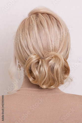 Female back with blonde hair and fashion hairstyle in beauty salon