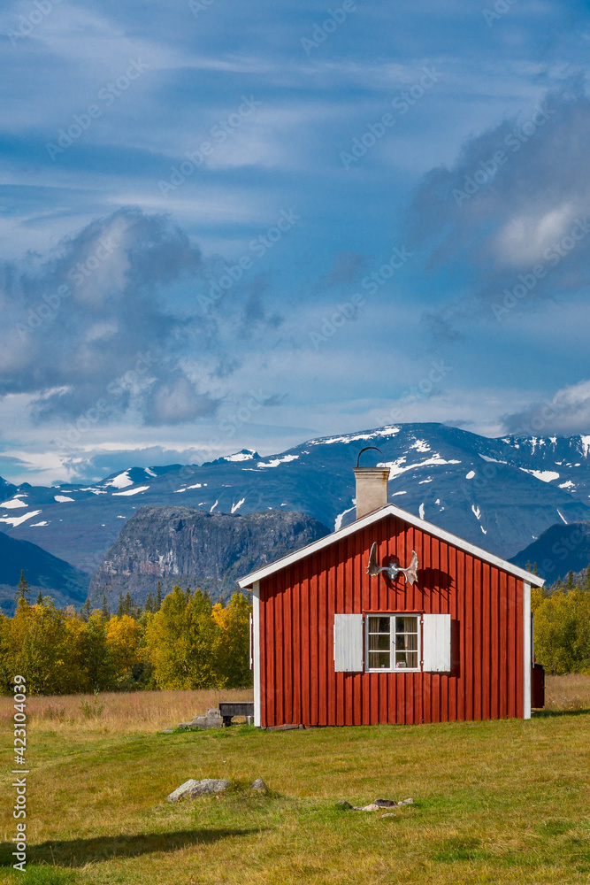Red wooden house in arctic wilderness. Aktse mountain cabin deep in Sarek National Park, Sweden. Antlers on the wall. Sunny day of autumn in the arctic. Fall colors in Lapland.