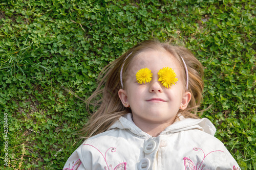 a little girl in the garden lies on the grass with flowers in her eyes