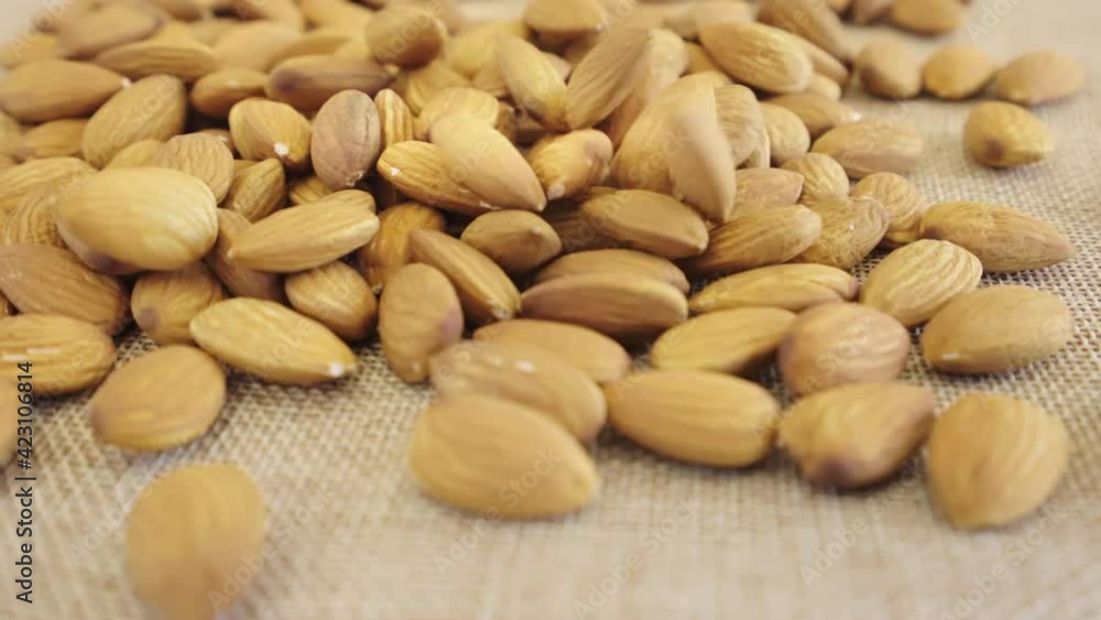 Close up almonds seed rotate on brown fabric, Slow motion almond kernels rotation with brick background, Front view almond nuts rotating, Concept whole grains of food for healthy. Close up almonds seed rotate on brown fabric, Slow motion almond kernels rotation with brick background, Front view almond nuts rotating, Concept whole grains of food for healthy.