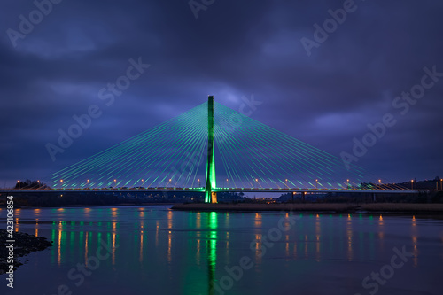 Modern line bridge illuminated with green lights for St. PAtricK in Waterford Ireland. Overnight.
