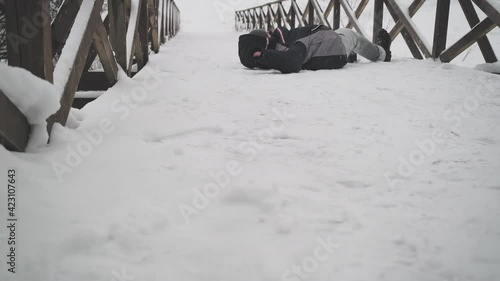 Man walks on a snow covered bridge, then he slips and falls hard hitting. The concept of accidental injuries, accidents and force majeure photo