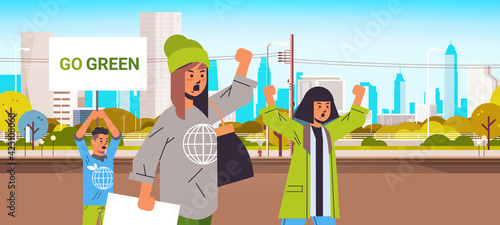 environmental activists holding posters go green save planet strike concept protesters campaigning to protect earth demonstrating against global warming portrait cityscape background horizontal