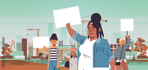 mix race activists holding placards with female gender sign feminist demonstration girl power movement rights protection women empowerment concept portrait construction site background horizontal
