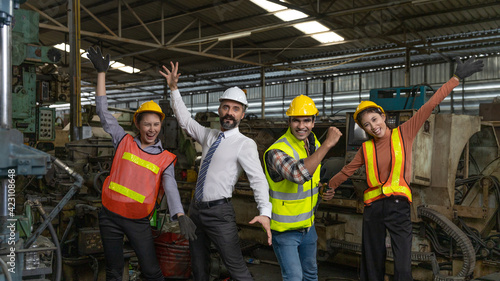 Group of factory workers or engineers with safety gears and hardhat express a great happiness after big business success or achievements