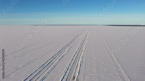 Aerial view of traffic on a winter road, cars driving on the icy ocean - reverse, drone shot photo