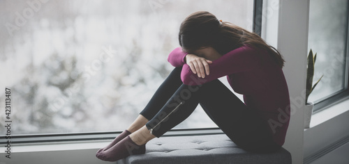 Sad crying young woman hiding face in sadness alone at home in isolation. Mental health problem social anxiety panic attack ptsd effects from the coronavirus pandemic. photo