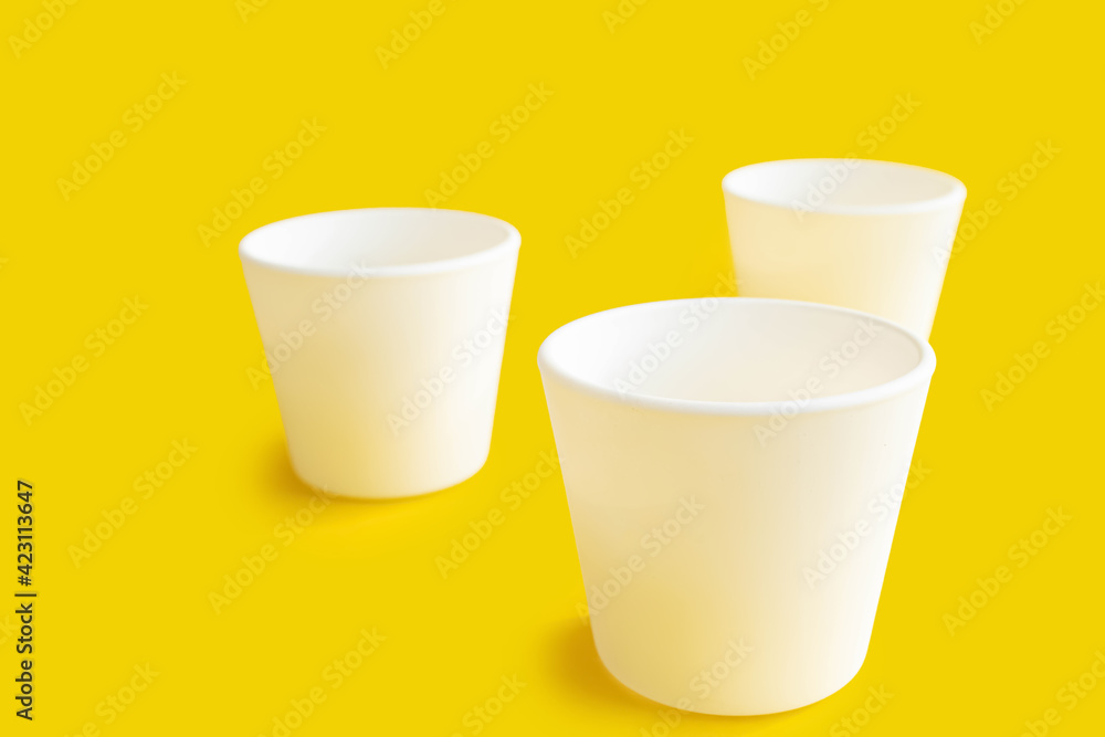 White pots empty on a yellow background. Empty jars on the table. White pots empty on a yellow background. Empty jars on the table.