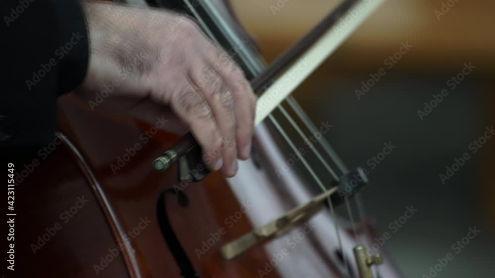 Musician hand playing cello on a classical music concert, closeup of instrumentist Musician hand playing cello on a classical music concert, closeup of instrumentist