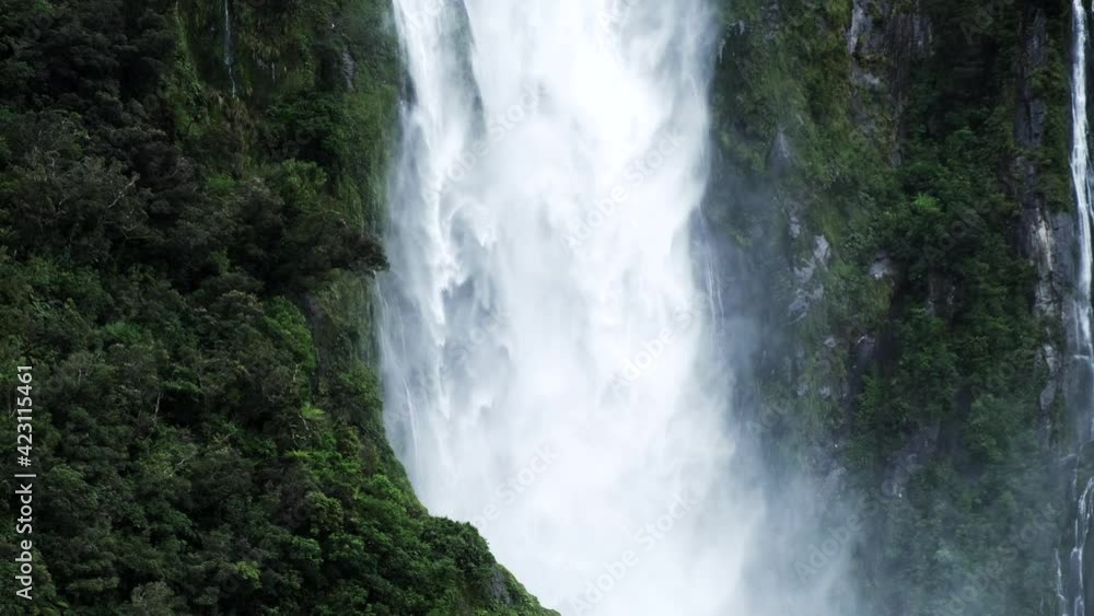 Powerful waterfall flows down green mountainside in fjord. Powerful waterfall flows down green mountainside in fjord.