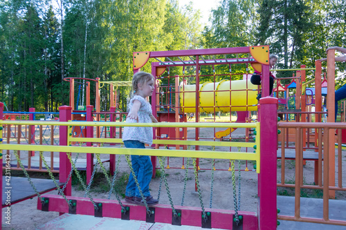 A girl is playing on a new modern playground on a nice warm day. 