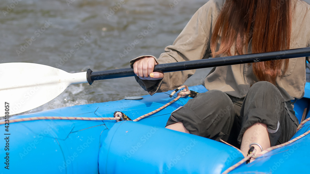 A woman holding a paddle on a blue rubber boat in the river White water rafting, kayaking, a relaxing holiday activity close to nature