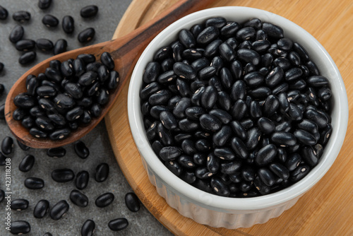 Bowl with black bean grains. Detail of wooden spoon and bamboo support. photo