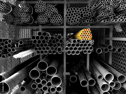 Multi size pvc pipe on the metal rack in yellow, black and white photo