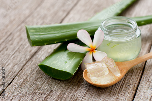 Aloevera gel with cactus green leaf and plumeria flower on wood table background.