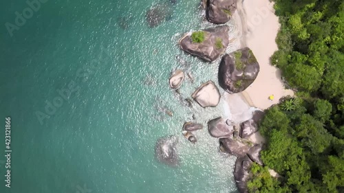 Gliding amidst the glistening turquoise sea, small beach of giant stones, and Atlantic rainforest in Angra dos Reis, Rio de Janeiro, Brazil photo