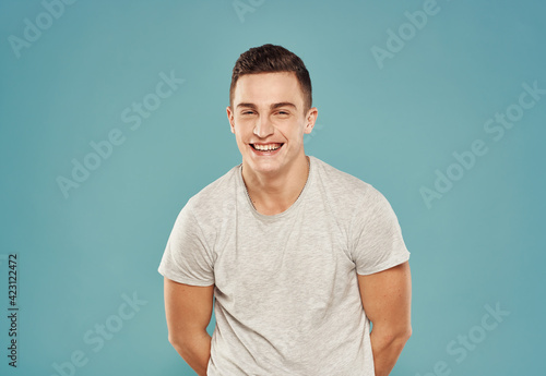 Cheerful man in T-shirt emotions gestures with hands blue background