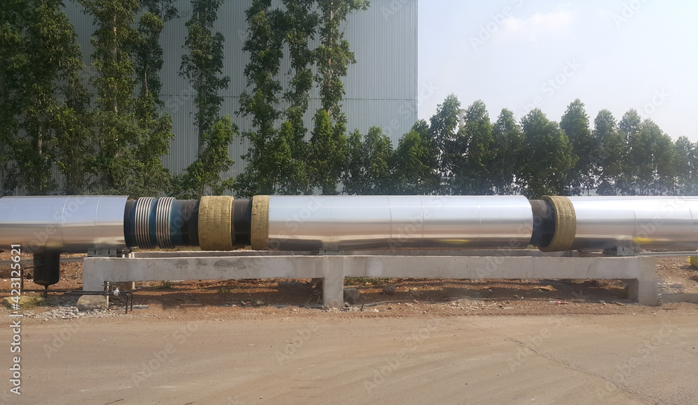 The new black metal pipe with insulated designed to carry pressurized steam is overground parallel to the road. The new black metal pipe with insulated designed to carry pressurized steam is overground parallel to the road.