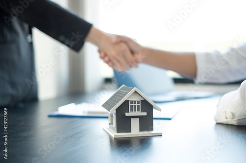 Businessmen and brokers real estate agents shake hand after completing negotiations to buy houses insurance and sign contracts. Home insurance concept