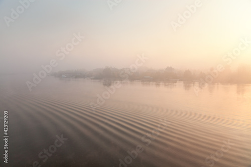 Foggy sunrise over the calm river  silhouettes of houses on the horizon  abstract background. The river Samara