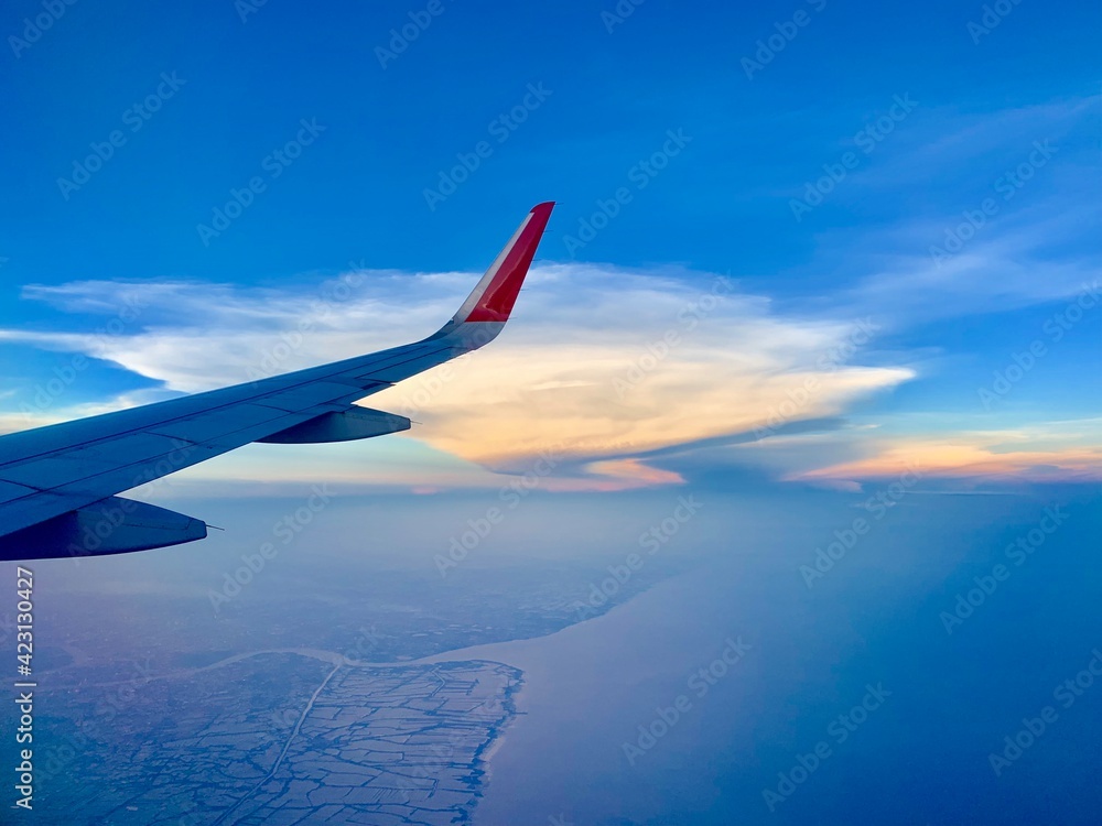 Obraz premium View of airplane wings and golden clouds as background.