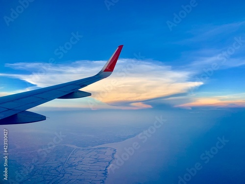 View of airplane wings and golden clouds as background.