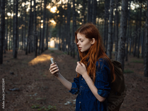 Happy woman in pine forest with mobile phone navigator tourism model