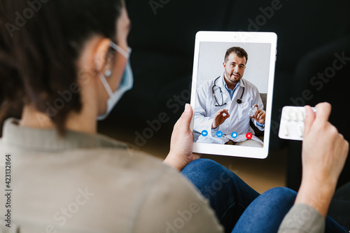Latin woman talking with a doctor online using digital tablet and computer, feeling bad at home. Concept of telemedicine and patient in Mexico city