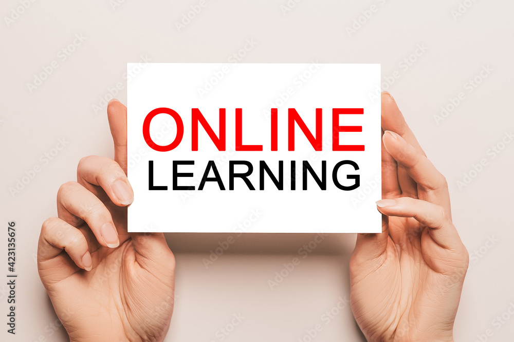 Female hands hold card paper with text online learning on a yellow background. Education and study concept Female hands hold card paper with text online learning on a yellow background. Education and study concept
