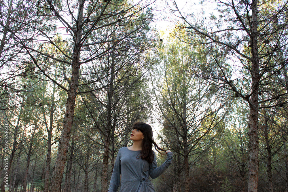 Young brunette girl posing in the forest with trees in the background Young brunette girl posing in the forest with trees in the background