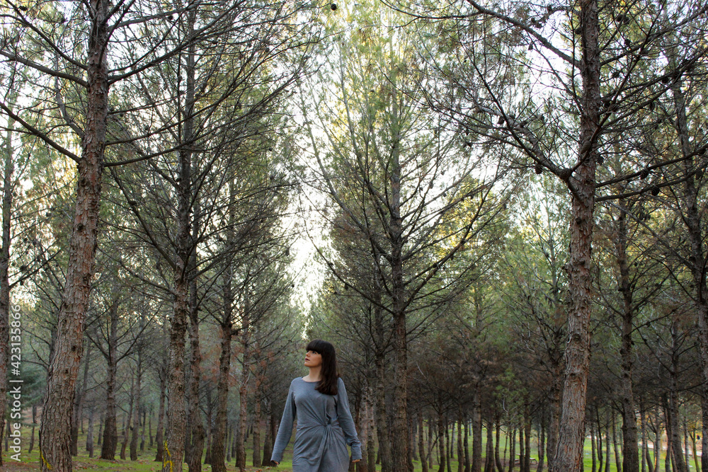 Young brunette girl posing in the forest with trees in the background Young brunette girl posing in the forest with trees in the background