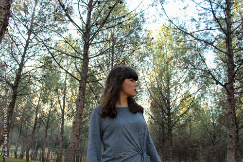 Young brunette girl posing in the forest with trees in the background
