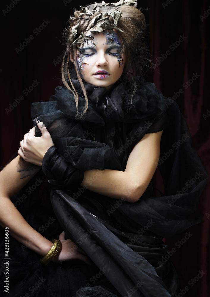 Halloween and party concept. Beautiful Gothic Princess. Young woman with creative make up and hair style over dark red background. Halloween and party concept. Beautiful Gothic Princess. Young woman with creative make up and hair style over dark red background.