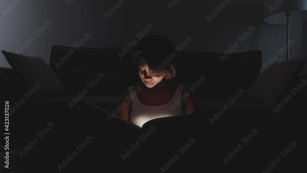 Portrait of young female sitting at home on the floor and reading a book, warm light, self-isolation during the pandemic, mystical lighting effect. Portrait of young female sitting at home on the floor and reading a book, warm light, self-isolation during the pandemic, mystical lighting effect.