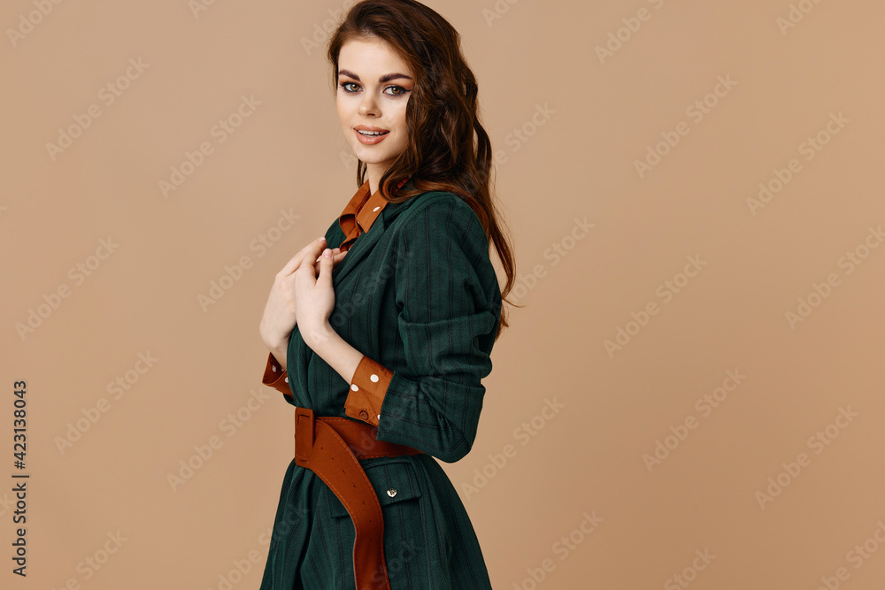 Fototapeta premium A woman in a black jacket and a red shirt on a beige background gestures with her hands the hairstyle model