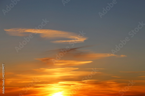 Sunset on colorful dramatic sky, white clouds in the orange sunlight. Picturesque landscape for background