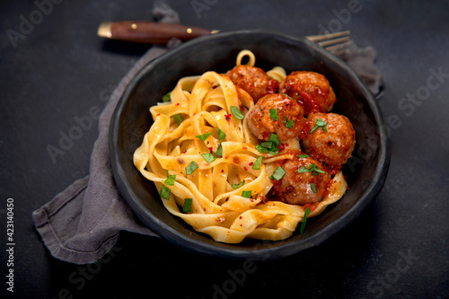 Tagliatelle with meatballs and tomato sauce on dark background. Italian food concept.